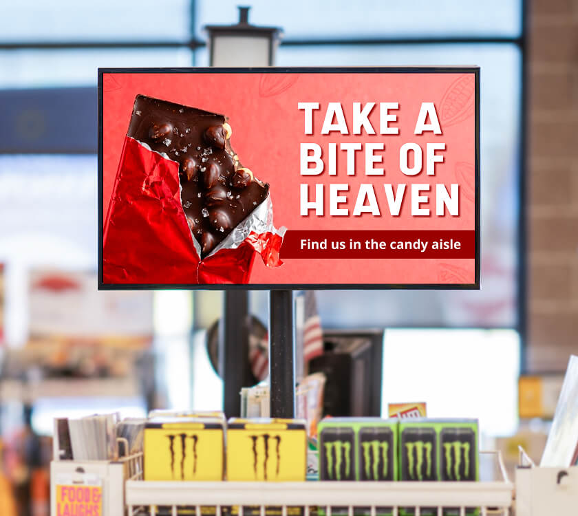 Image of a digital screen showcasing a brand’s holiday candy at the grocery store front end